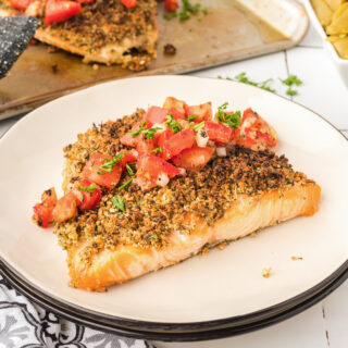 A photo of herb crusted salmon on a white plate