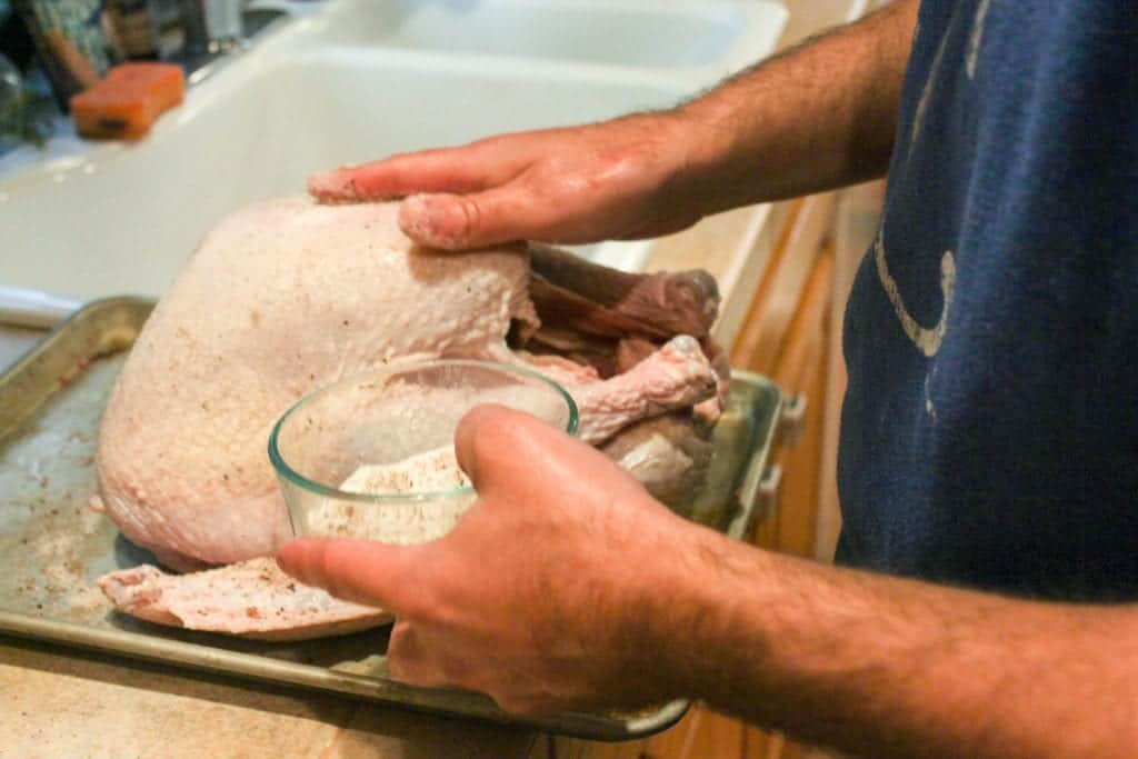 a photo of hands rubbing a whole raw turkey