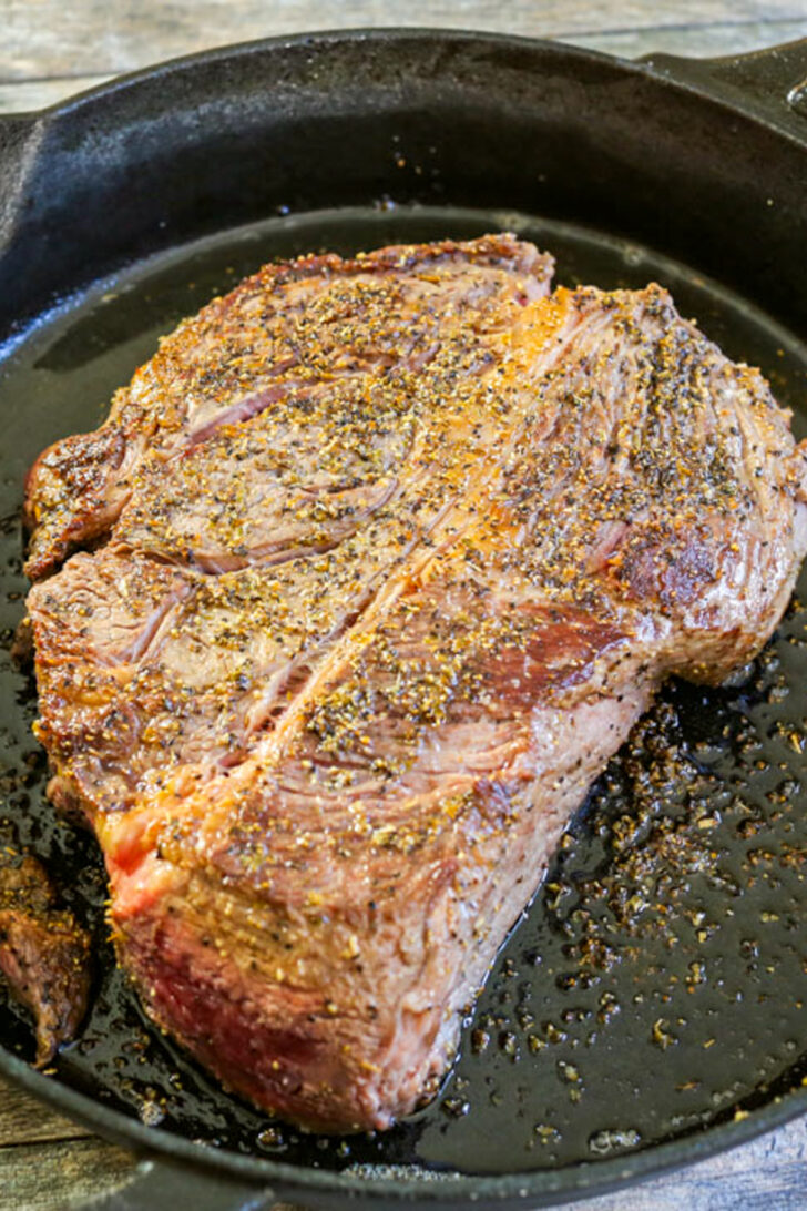 a photo of a chuck roast being seared in a cast iron skillet