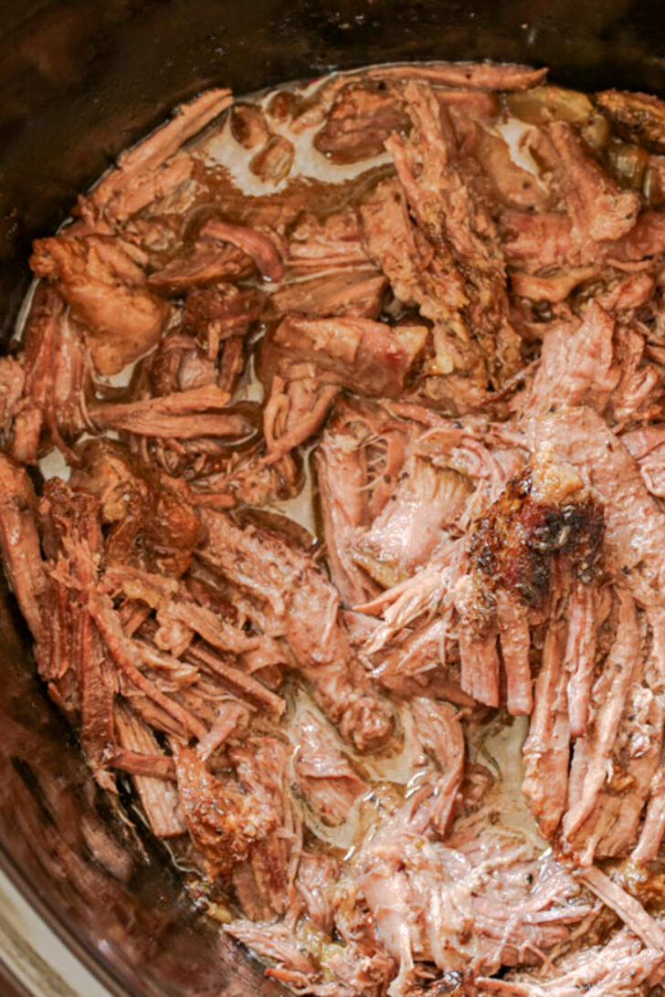 a photo of shredded beef with juice in a crockpot