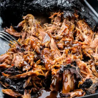 a close up photo of smoked pulled pork, shredded with a fork