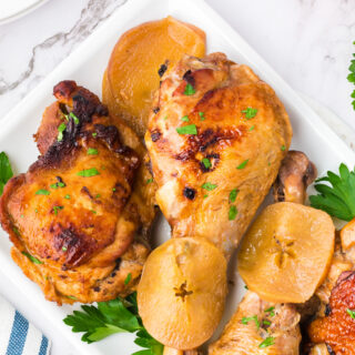 A photo of oven roasted turkey legs and turkey thighs with apple slices