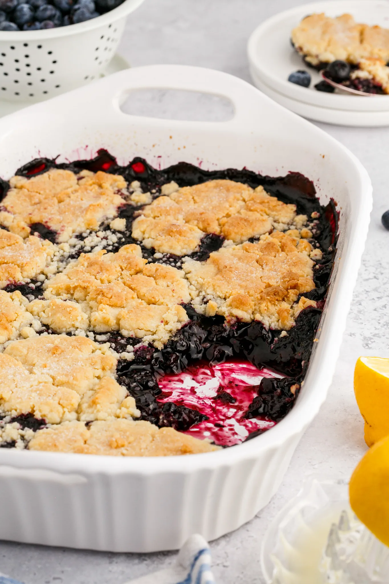 A photo of half eaten blueberry cobbler in a large casserole dish