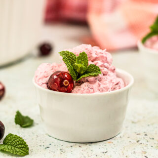 a photo of cranberry fluff salad in a small container with mint garnish