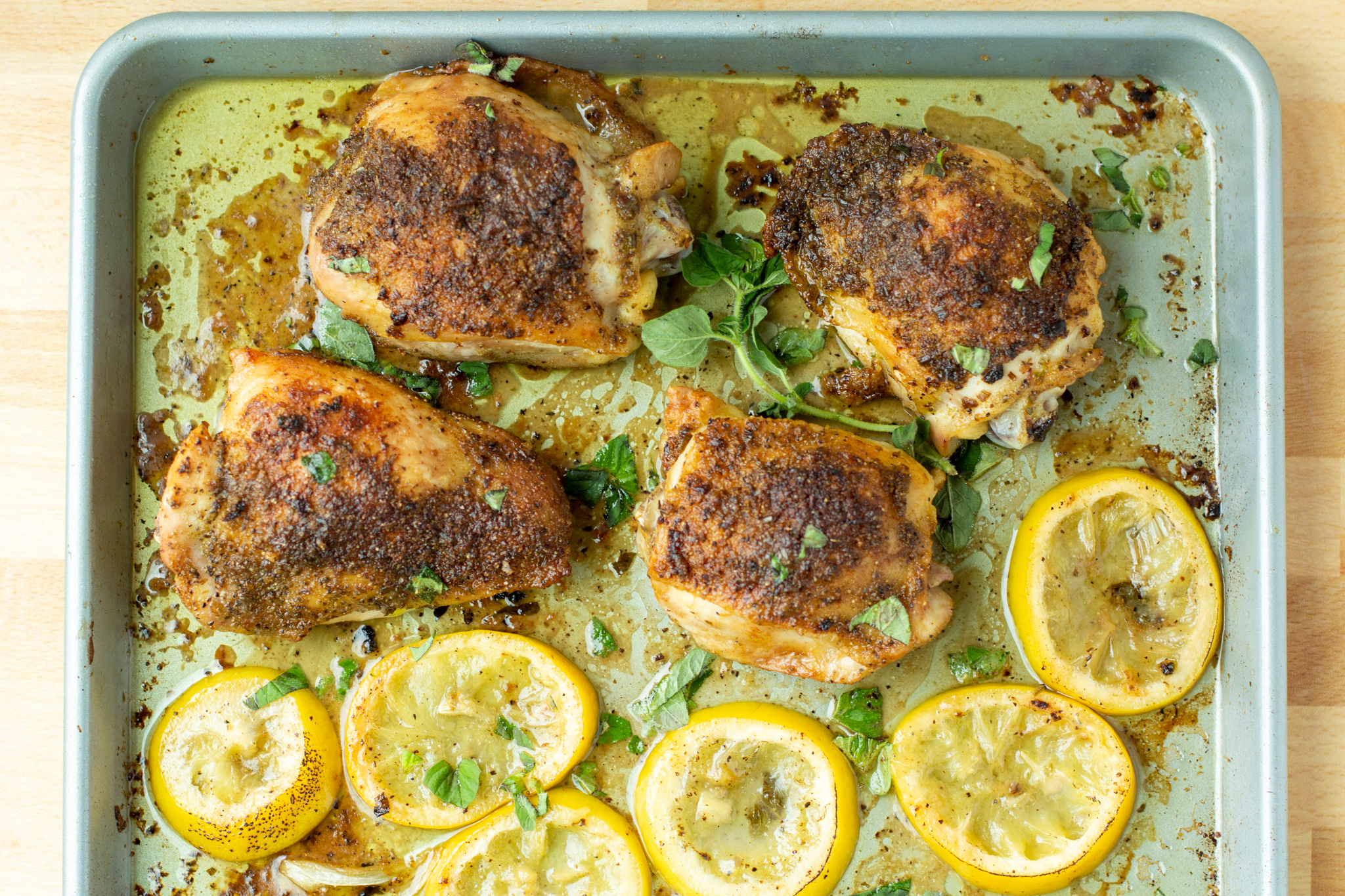 a photo of roasted chicken thighs, roasted fennel and lemon on a baking tray