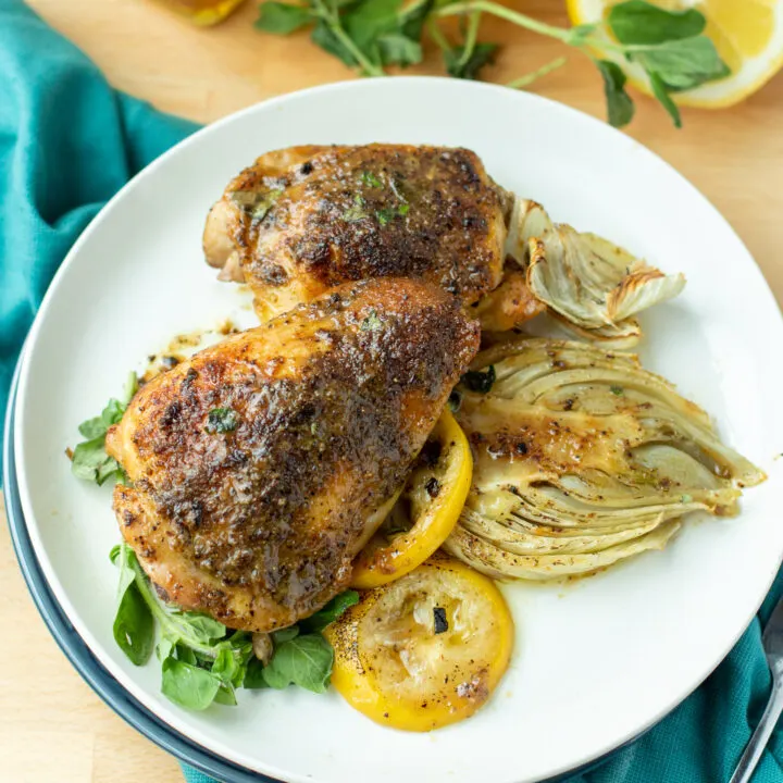 a photo of Roasted Greek Chicken Thighs with Charred Lemon and Fennel on a white plate