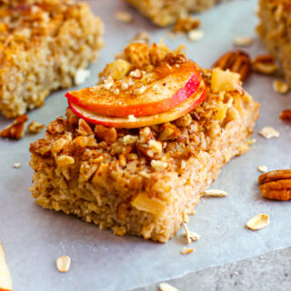 A photo of a baked oatmeal bar topped with apples and nuts