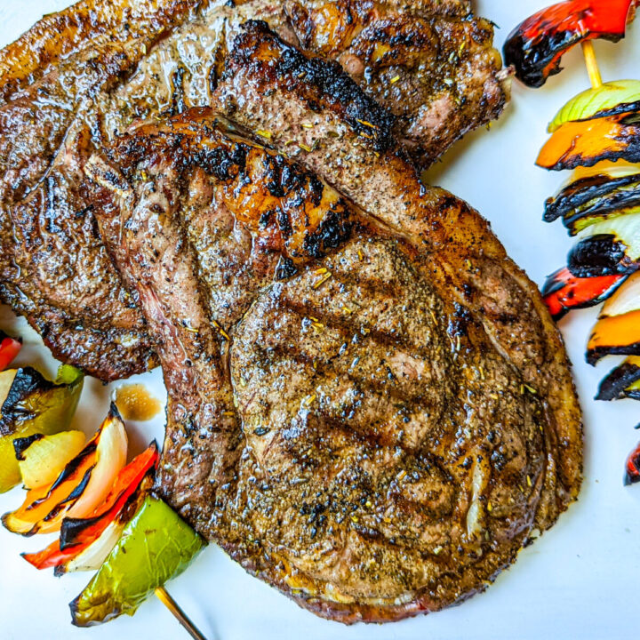 A photo of a grilled ribeye steak with grilled vegetable kabobs