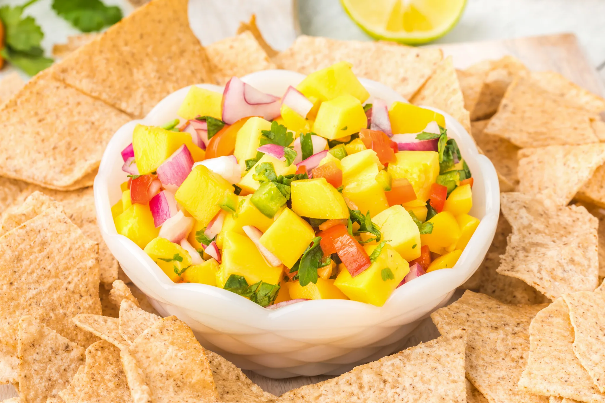 A close up photo of a white bowl with mango salsa in it 