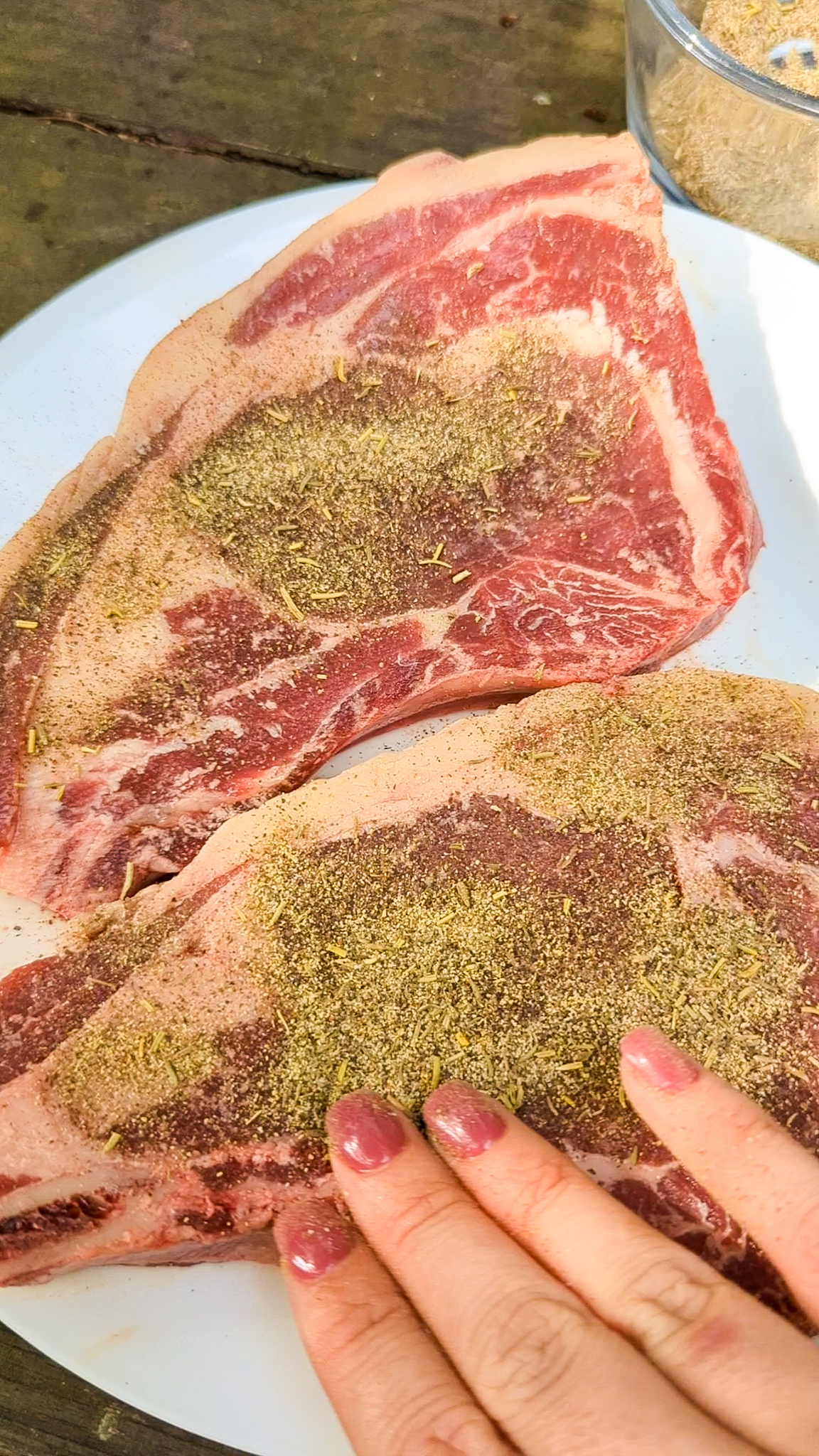 spice rub being applied to steaks
