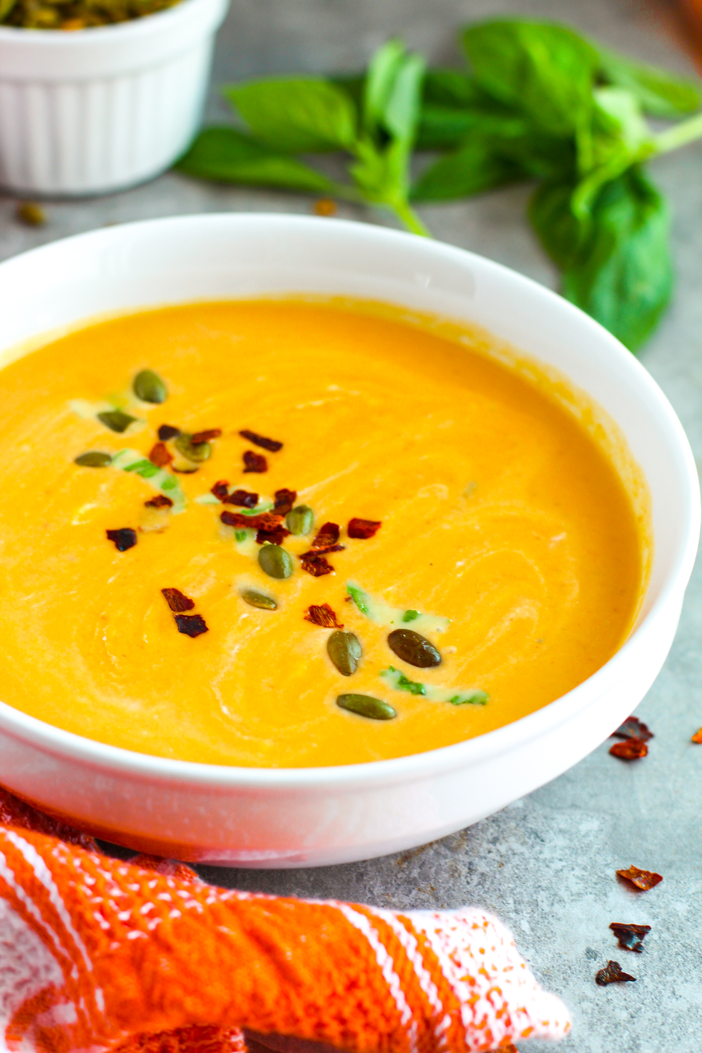 A photo of pumpkin soup garnished with pepitas and chili flakes