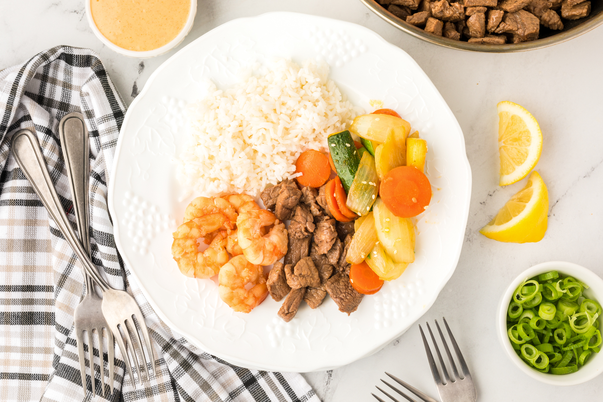 A photo of hibachi steak, shrimp, vegetables and rice on a white pate