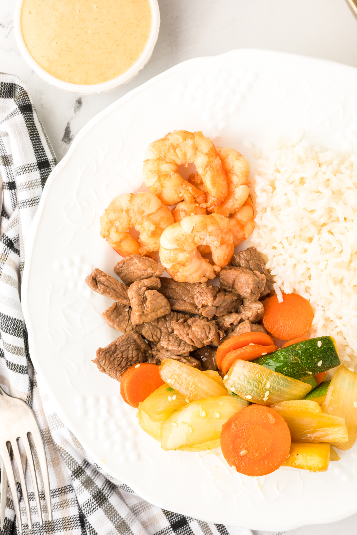 A photo of a white plate with hibachi steak, shrimp, veggies and rice