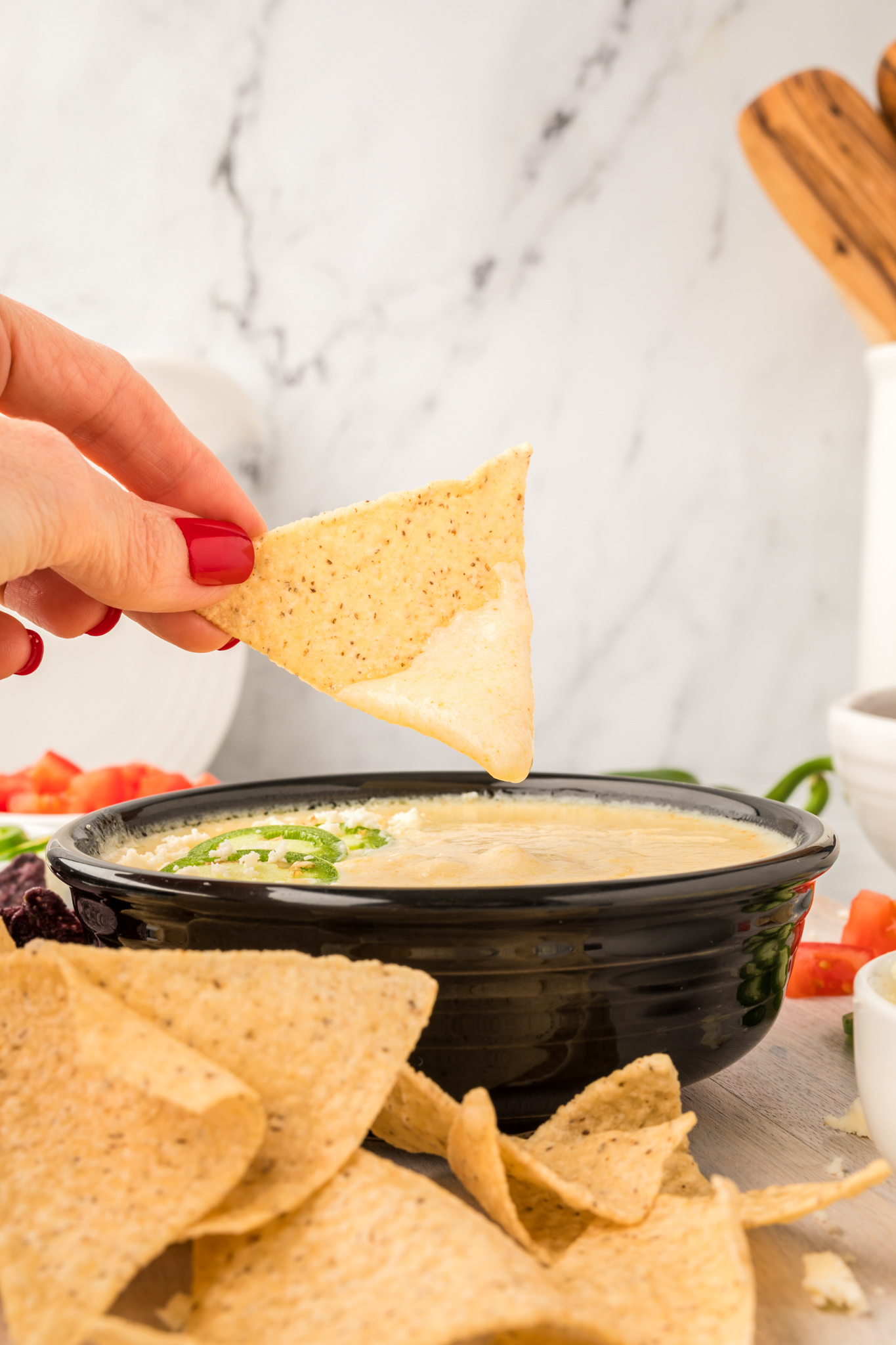 A photo of a tortilla chip being dipped into queso dip