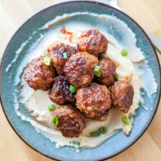 an overhead photo of barbecue pork meatballs on a plate of mashed potatoes