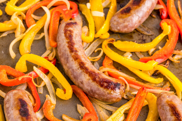 a phot of roasted bratwursts peppers and onions