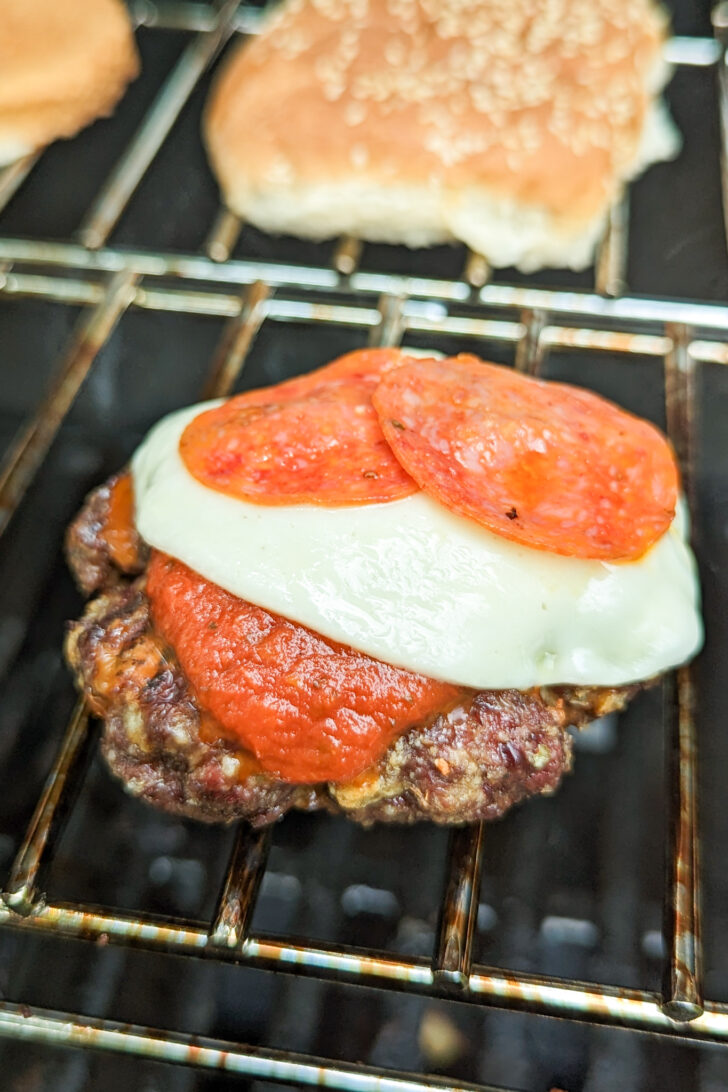 a photo of a pizza burger topped with cheese and pepperoni on a grill