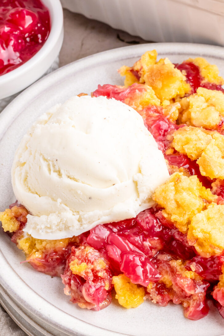 a photo of cherry cobbler on a plate with ice cream