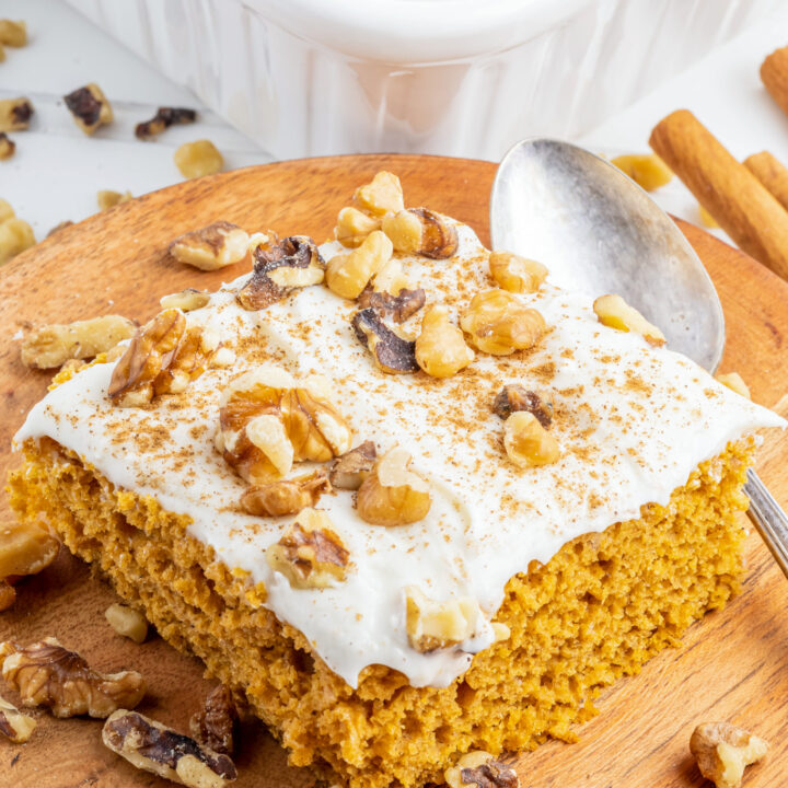 a photo of a slice of pumpkin sheet cake with cream cheese frosting and walnuts