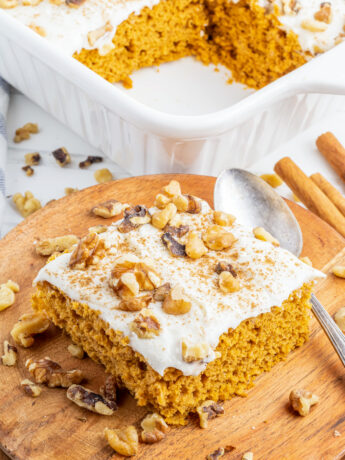 a photo of a slice of pumpkin cake with cream cheese frosting and walnuts