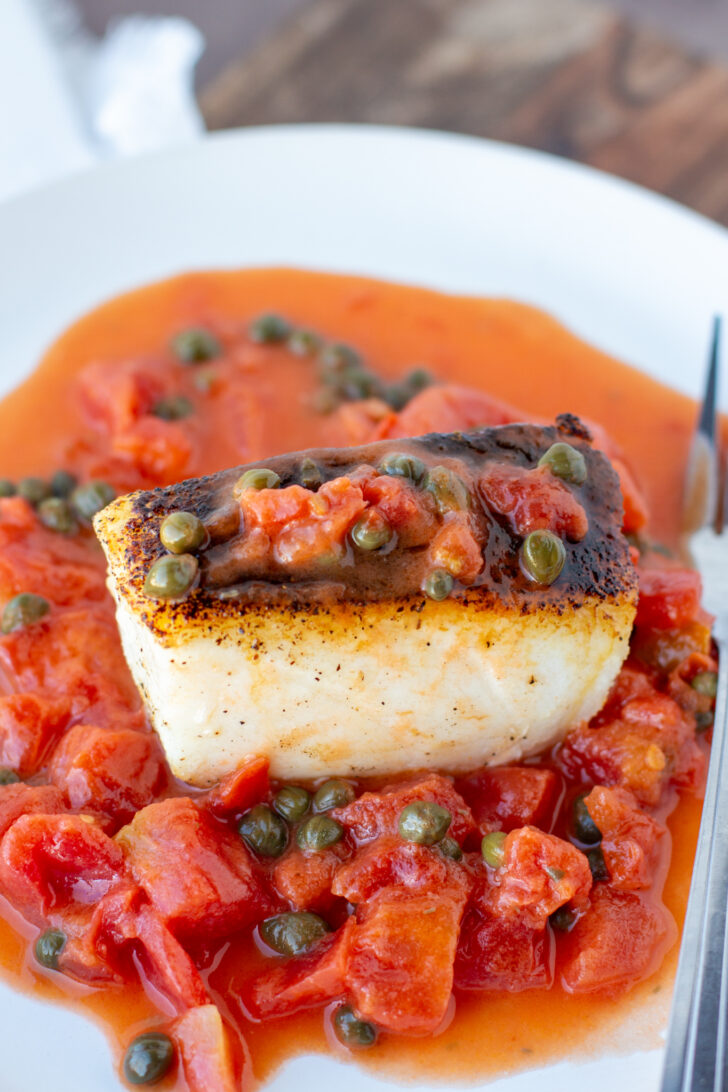 an overhead photo of pan seared seabass on a plate with tomato caper sauce