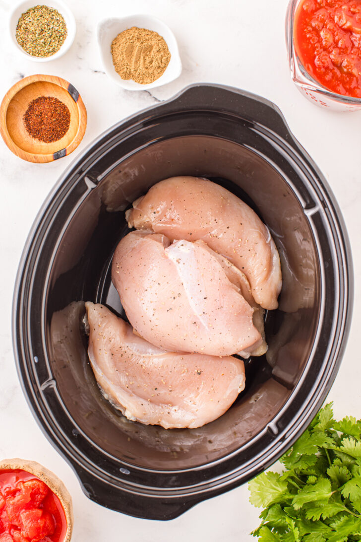 a photo of raw chicken breasts in a crockpot