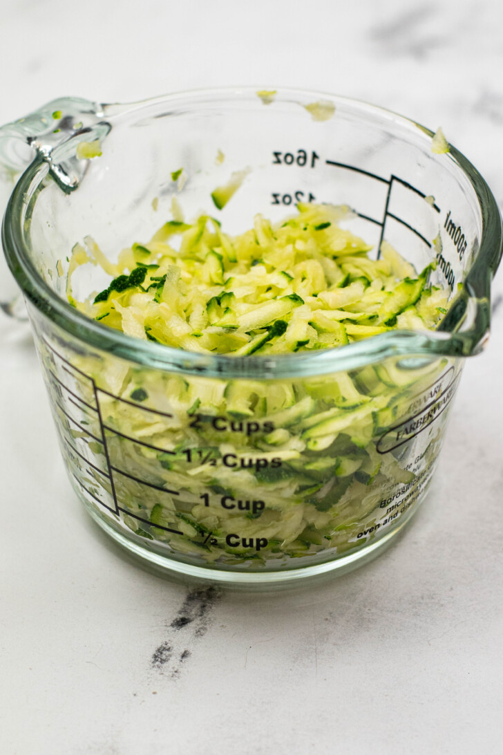 a measuring cup filled with shredded zucchini,