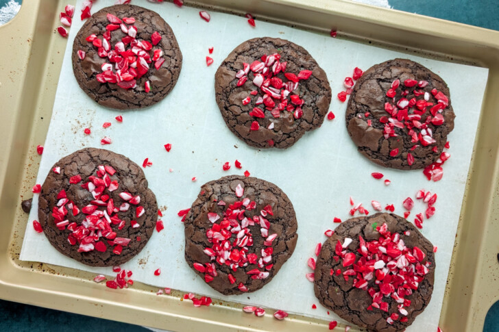 a cookie sheet fulled of chocolate cookies with peppermint on top