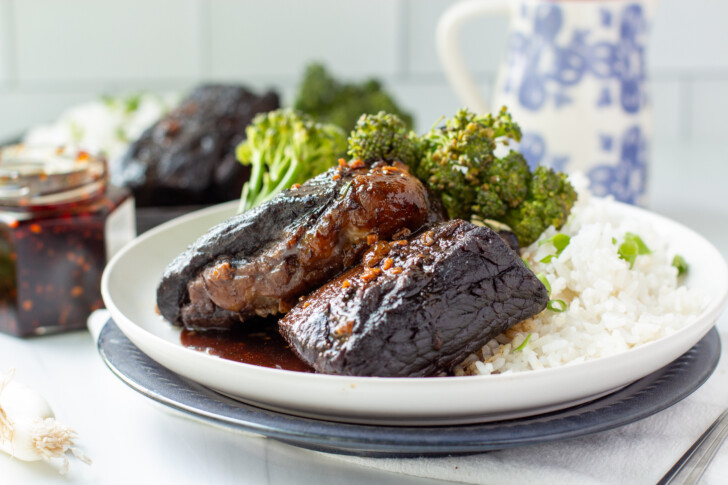 a horizontal photo of beef short ribs on a white plate