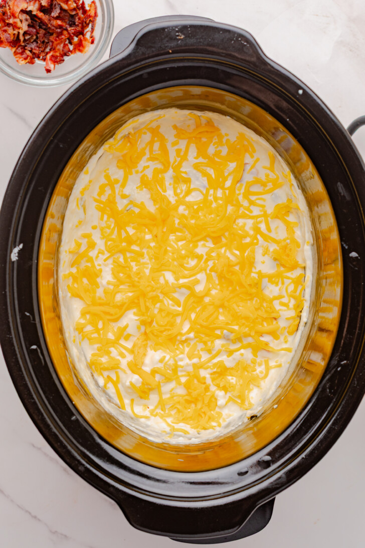shredded cheddar cheese on top of a creamy dip