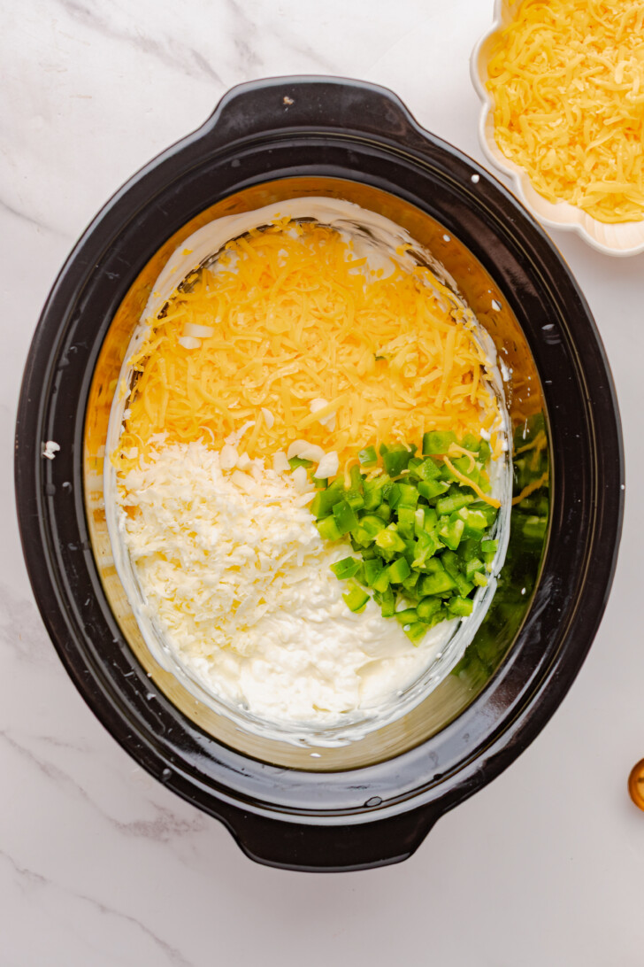 cheese and jalapenos being mixed into a creamy dip