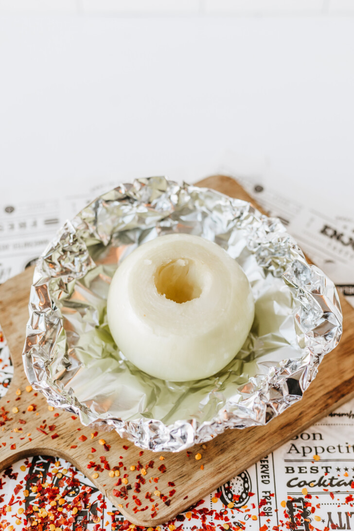an onion in aluminum foil with the core removed