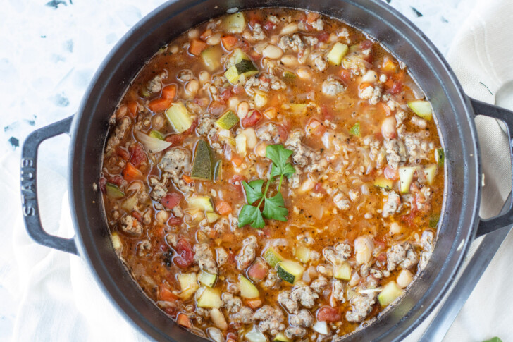 a black dutch oven filled with italian sausage zucchini soup