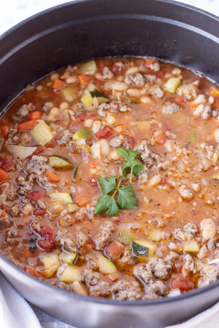 a black dutch oven filled with italian sausage zucchini soup