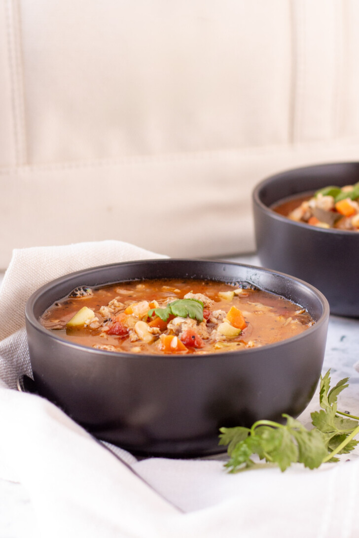 a black bowl filled with italian sausage soup