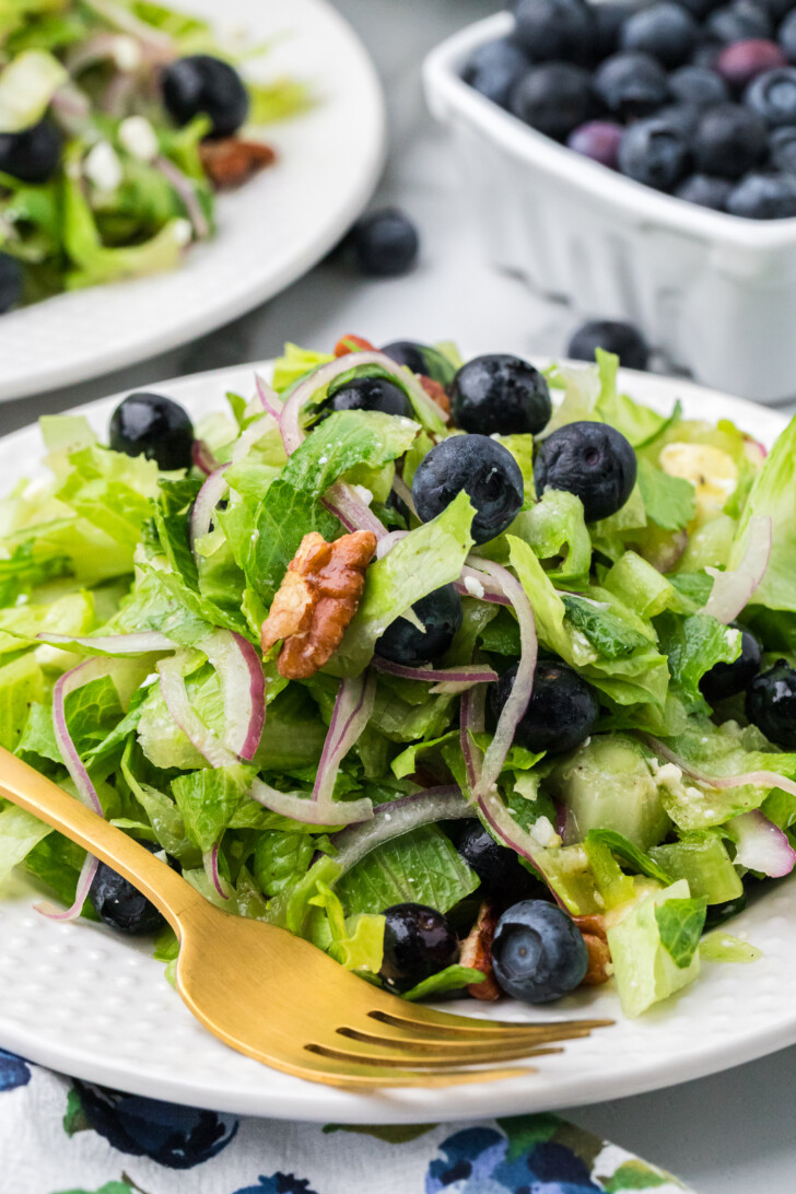 a close up photo of a salad with onions, blueberries and feta cheese