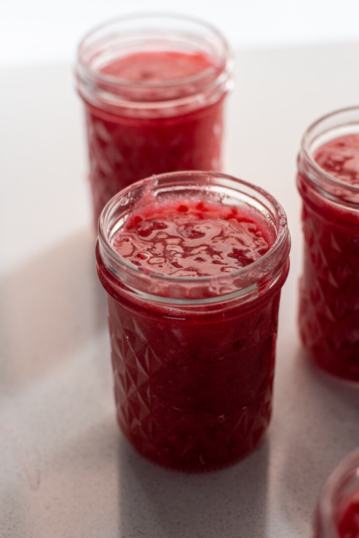 open jars of raspberry jam on a counter