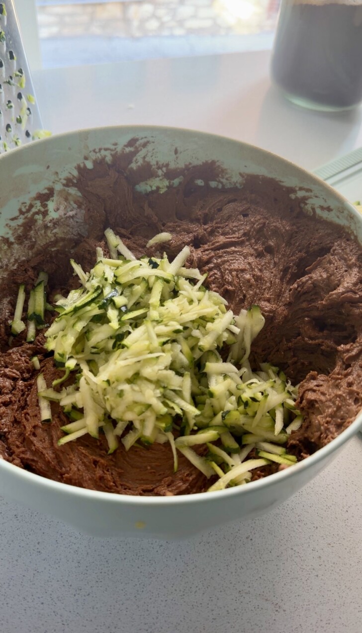 Shredded zucchini in a bowl of chocolate cake batter