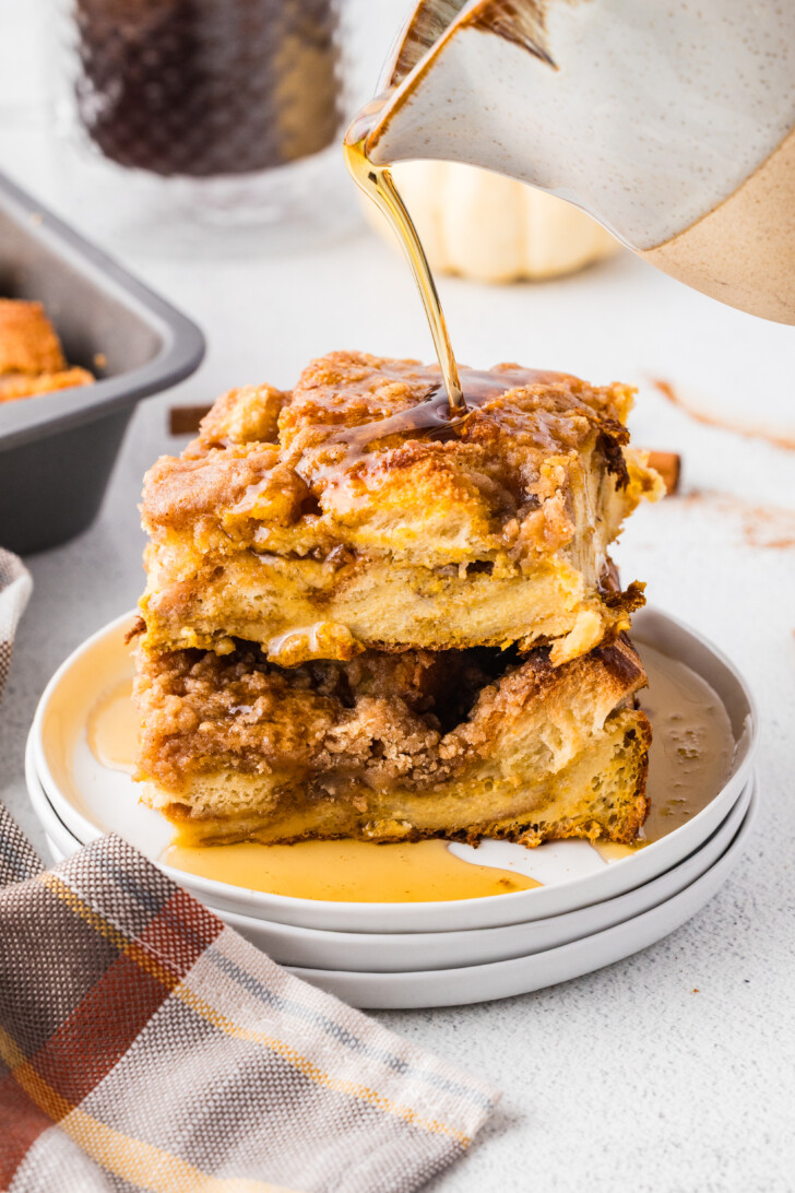 syrup being poured over the top of a slice of pumpkin french toast casserole