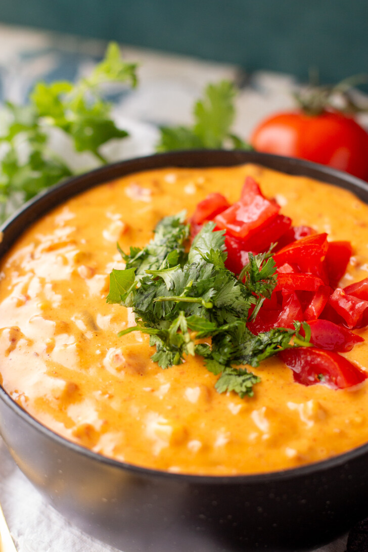 a bowl of spicy rotel dip topped with cilantro and tomato