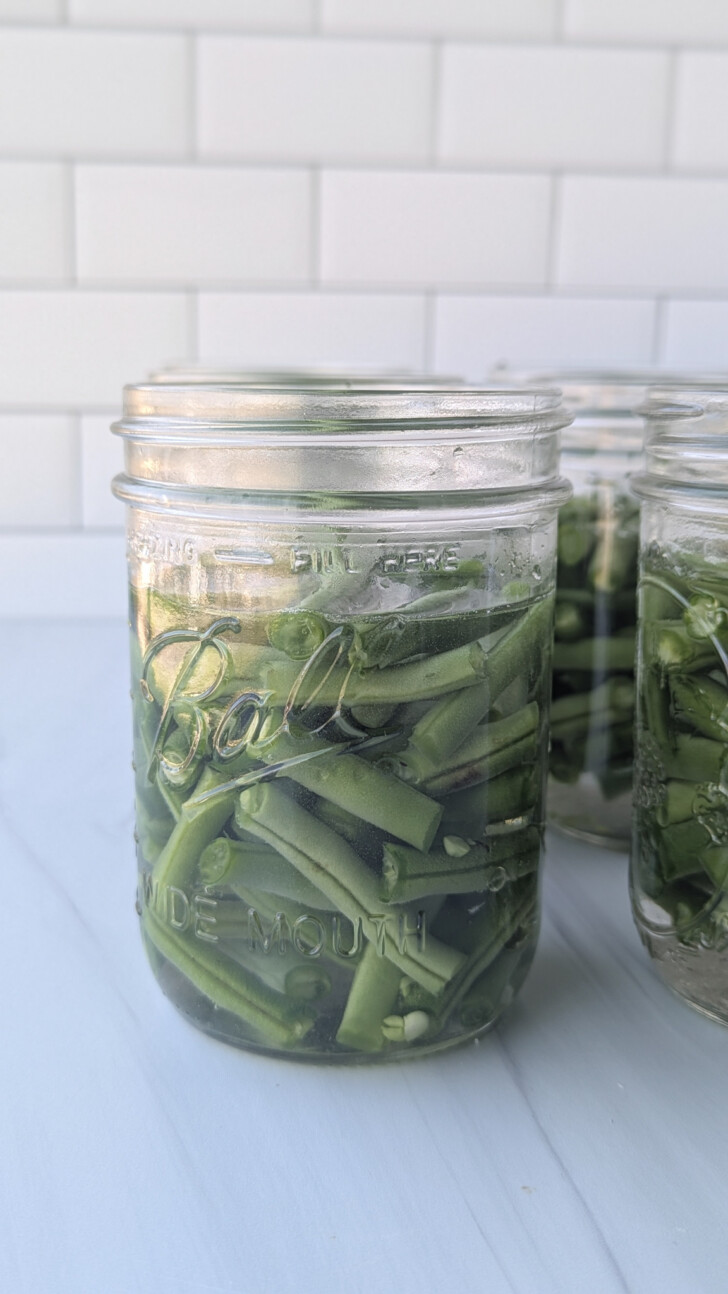 a jar filled with water and green beans