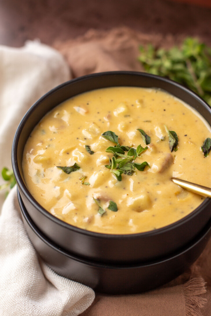 a black bowl filled with cheesy ham and potato soup