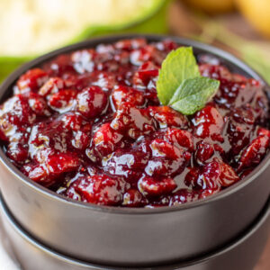 a black bowl filled with cranberry sauce and topped with fresh herbs