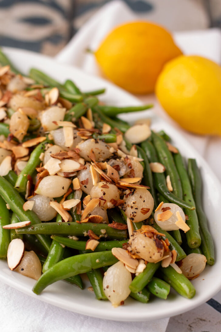a close up of green beans almondine on a white plate
