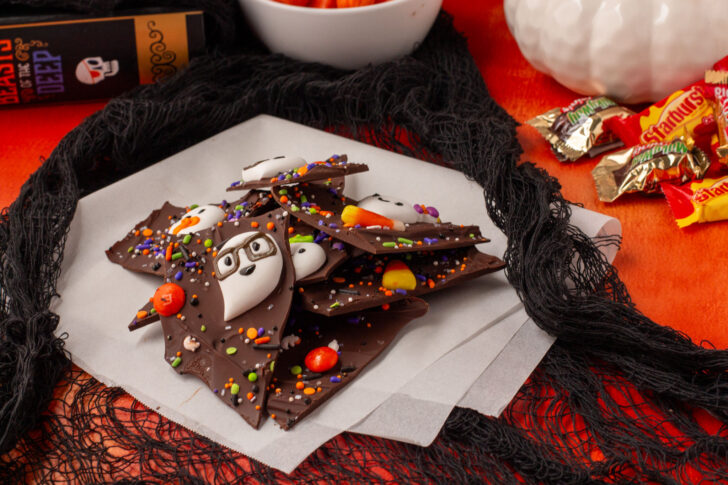 pieces of Halloween chocolate bark on white paper surrounded by Halloween decor