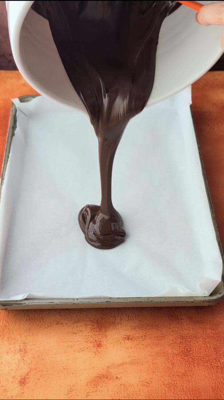 melted chocolate poured onto a parchment lined baking tray